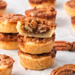 A stack of three pecan tarts with a bite missing from the one on top.