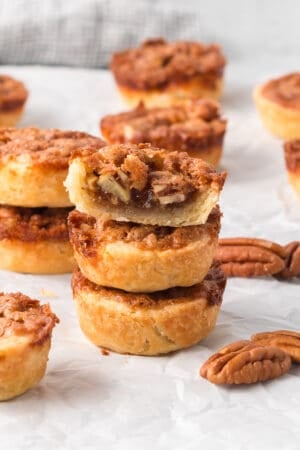 A stack of three pecan tarts with a bite missing from the one on top.