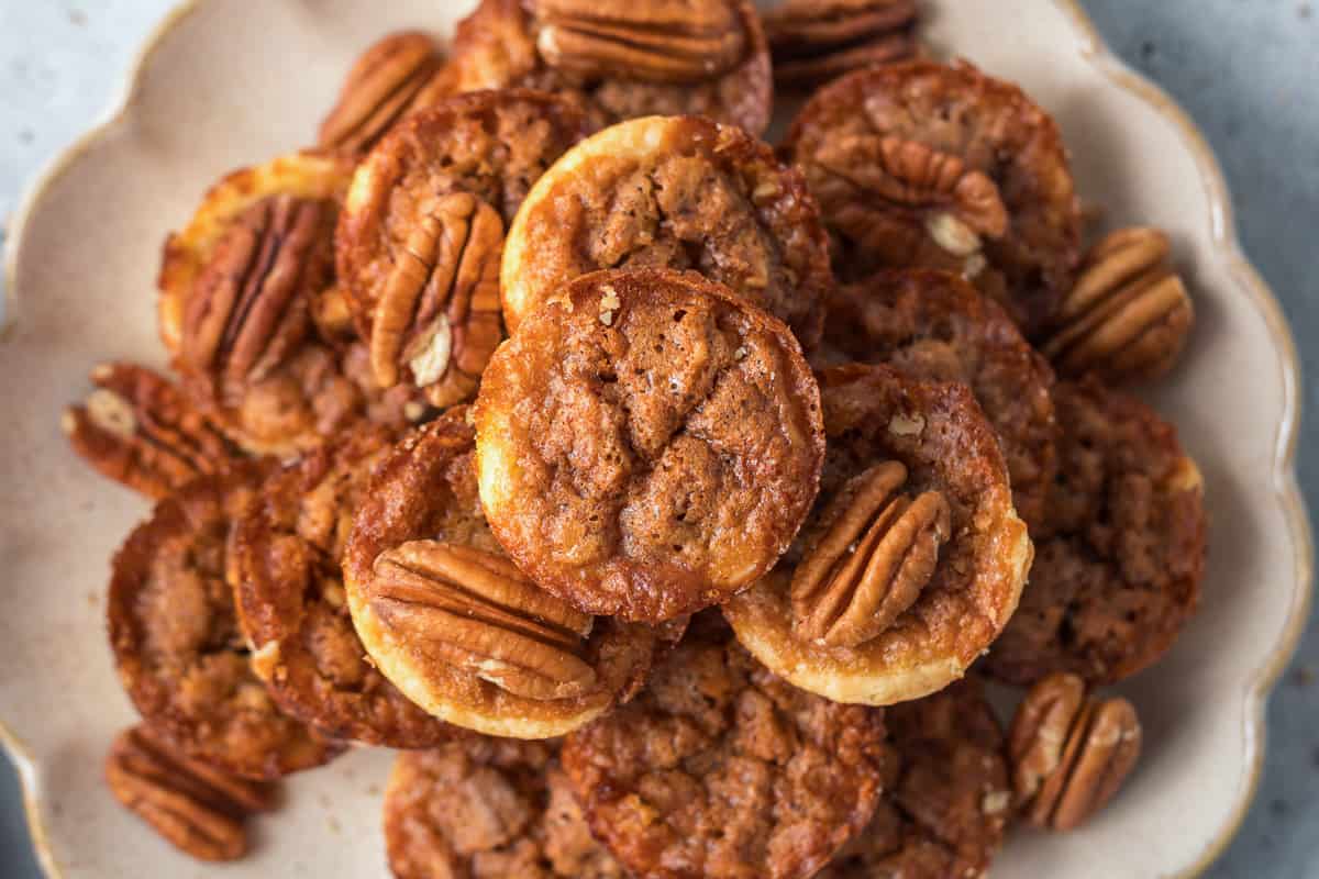 A top down shot of a pile of pecan tarts on a plate.