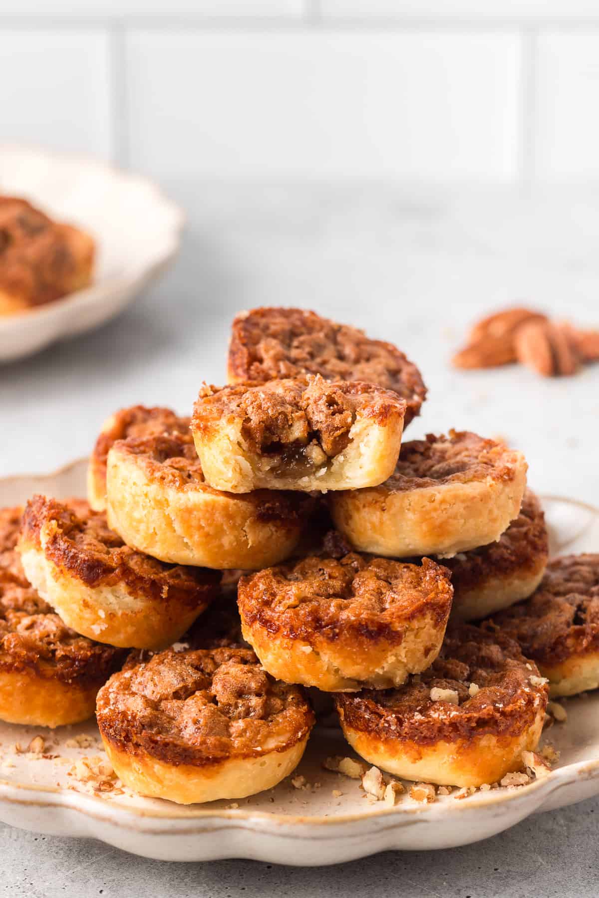 Pecan tarts piled on a plate with a bite missing from the one on top.