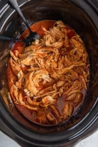 A top down shot of shredded BBQ chicken in a slow cooker.
