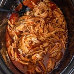 A top down shot of shredded BBQ chicken in a slow cooker.