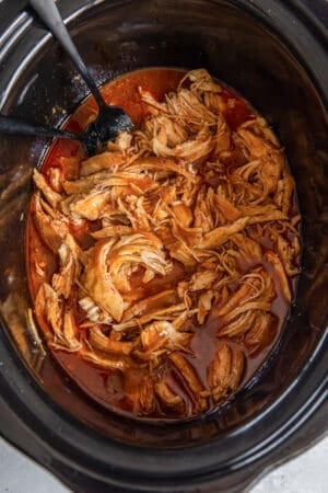 A top down shot of shredded BBQ chicken in a slow cooker.