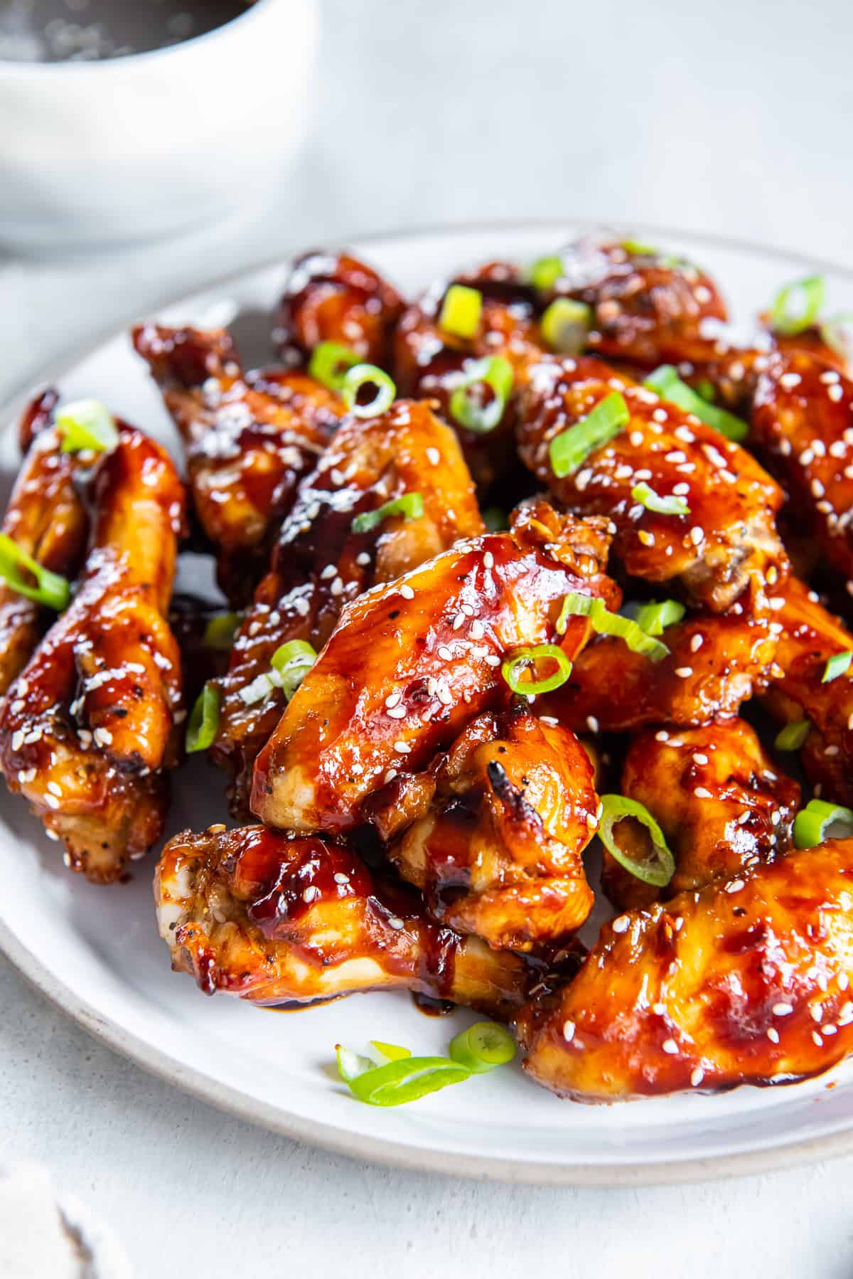 Sticky Asian wings on a white platter.