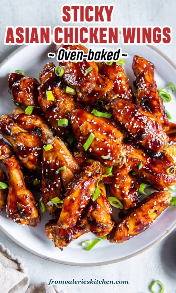 Glazed Asian chicken wings on a platter next to a small bowl of sliced green onions with text.