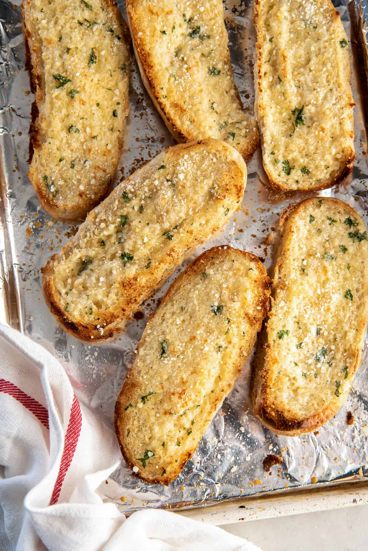 A top down shot of garlic bread made with hoagie rolls on a baking sheet.