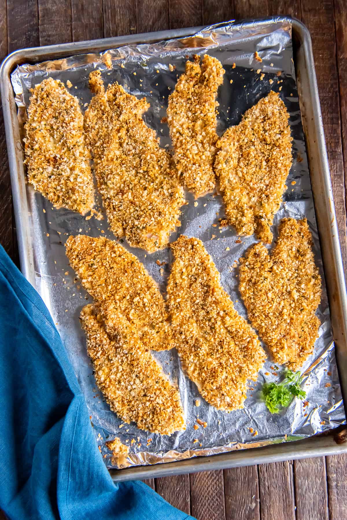 A top down shot of crispy baked fish filets on a foil lined baking sheet.