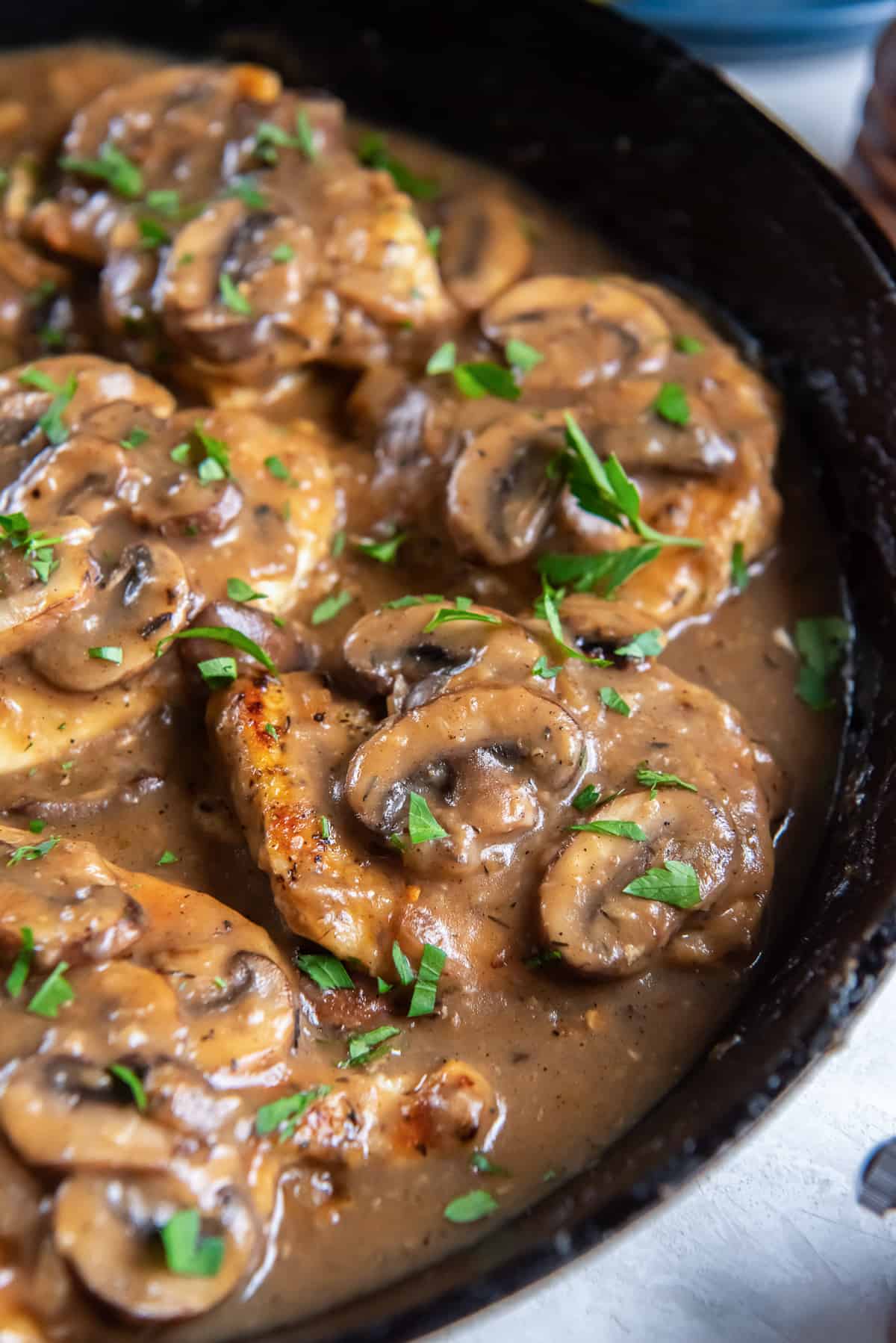 A close up of chicken marsala in a cast iron skillet.