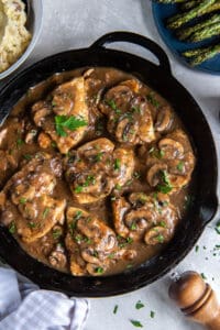 A top down close up shot of chicken marsala in a cast iron skillet.