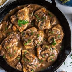 A top down close up shot of chicken marsala in a cast iron skillet.