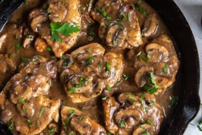 A top down close up shot of chicken marsala in a cast iron skillet.