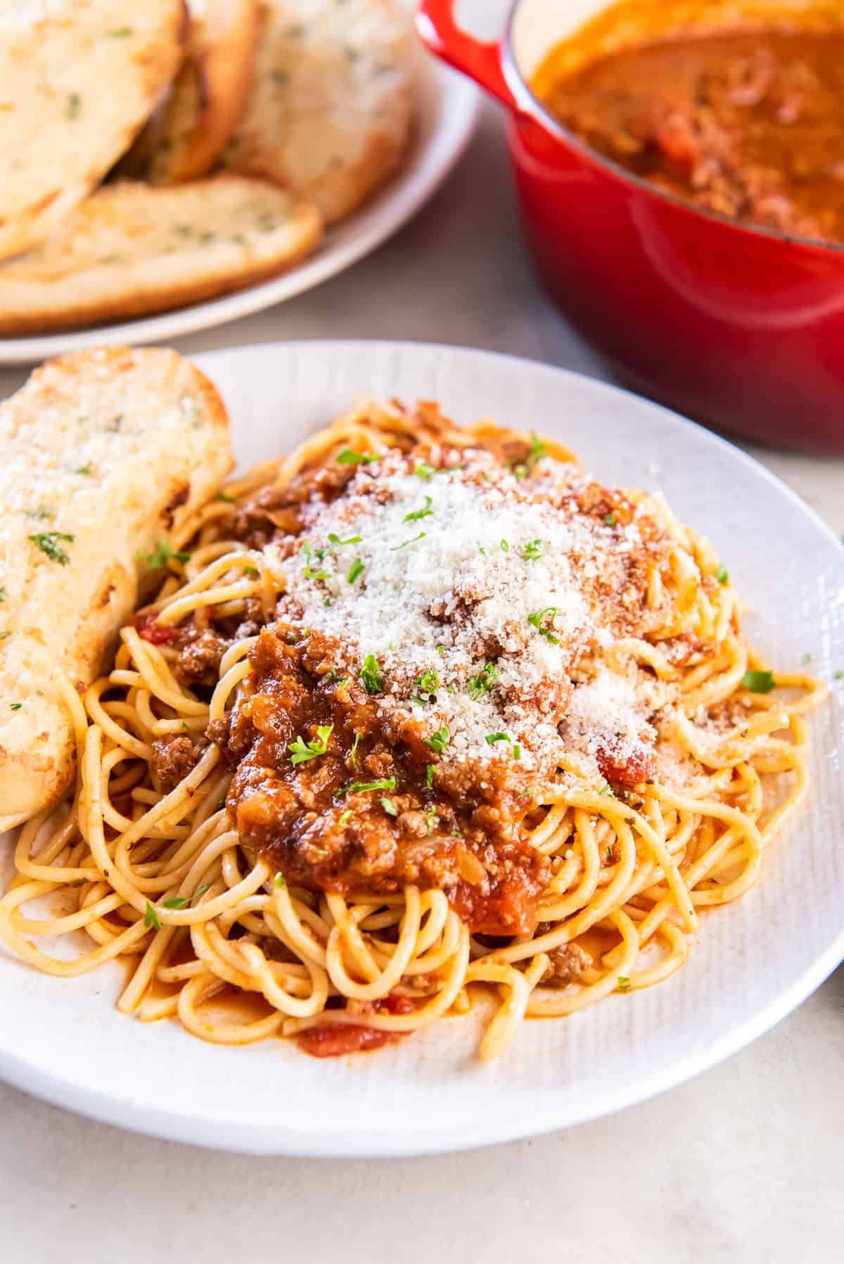 Spaghetti with sauce topped with Parmesan cheese on a white plate. 