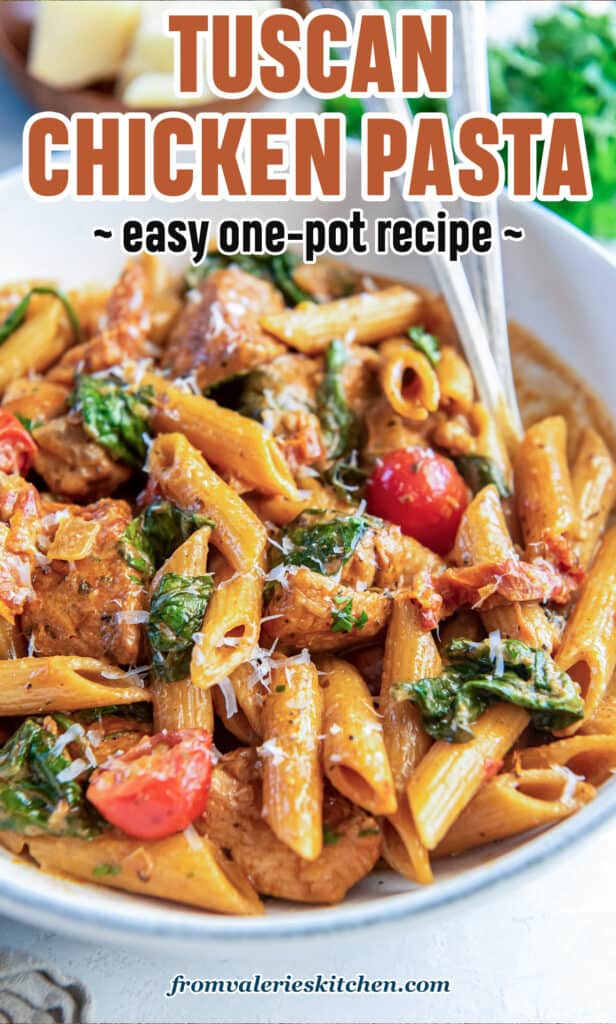 Forks resting in a bowl of tuscan chicken pasta with text.