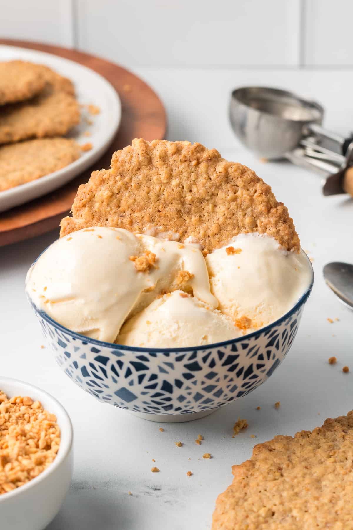 A crispy peanut cookie pressed into a bowl of vanilla ice cream.