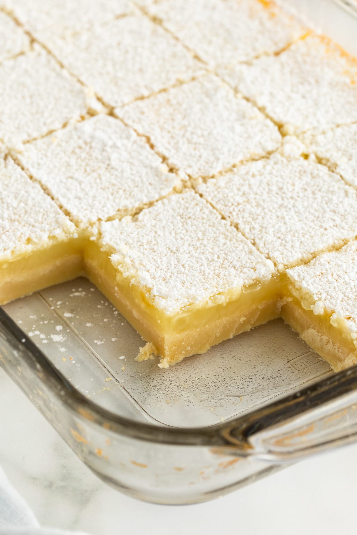 Sliced lemon bars in a baking dish with a few missing.