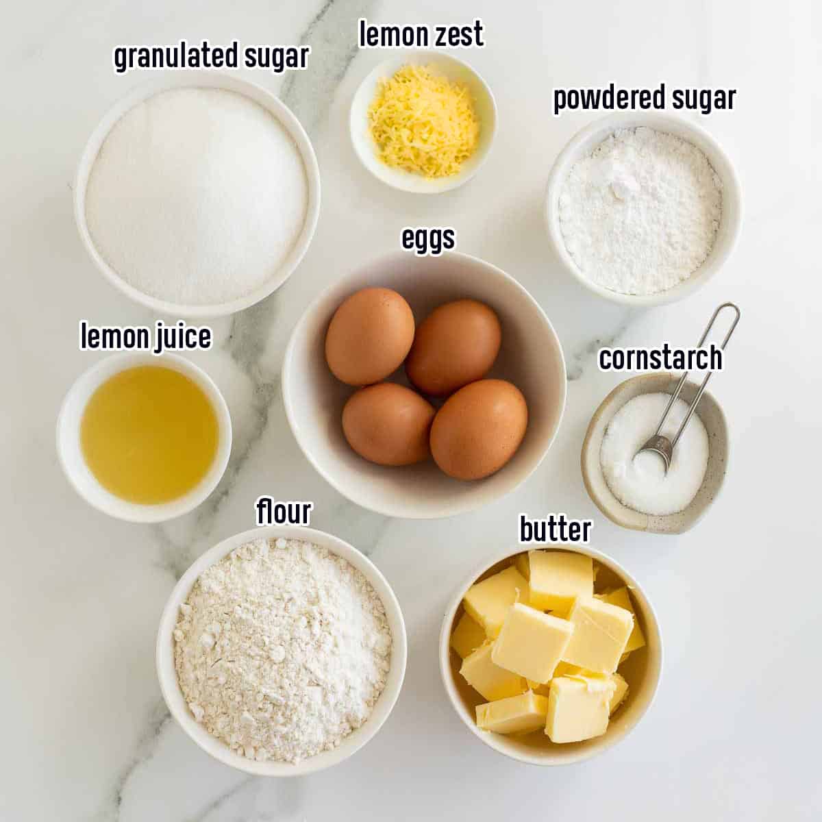 Lemon zest, lemon juice, eggs and other ingredients for lemon bars in bowls with text.