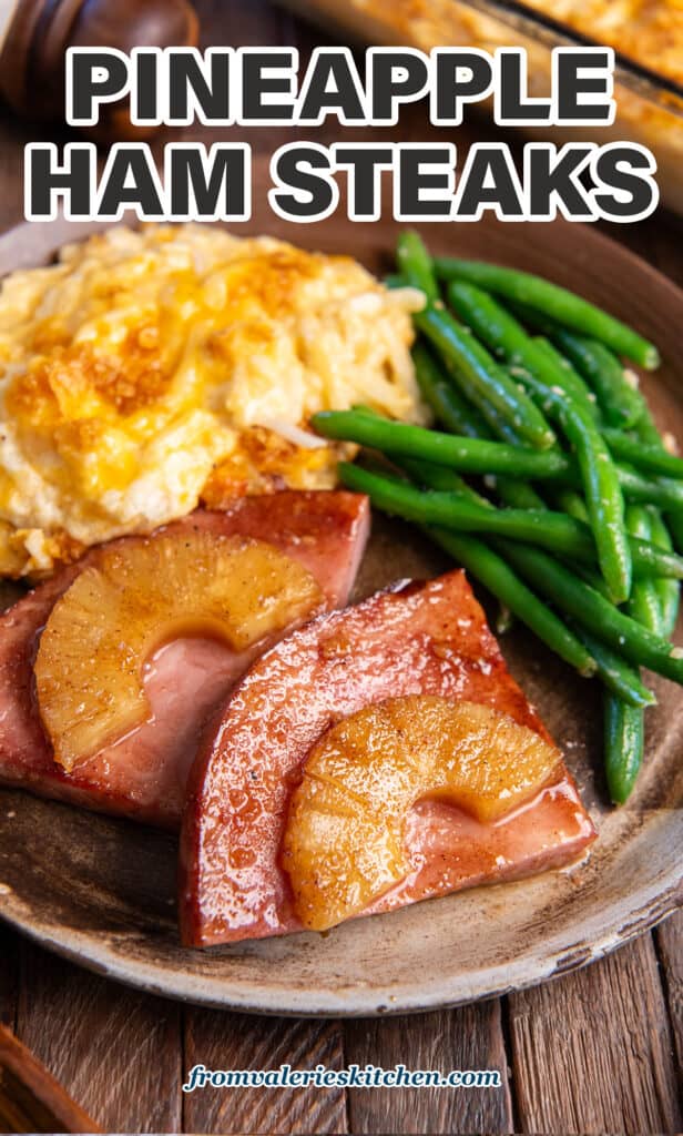 Pineapple glazed ham steak on a brown plate with cheesy hash browns and green beans with text.