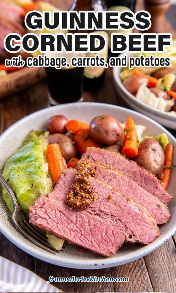 Slices of corned beef topped with a little stone ground mustard in a bowl in cabbage, carrots, and potatoes with text.
