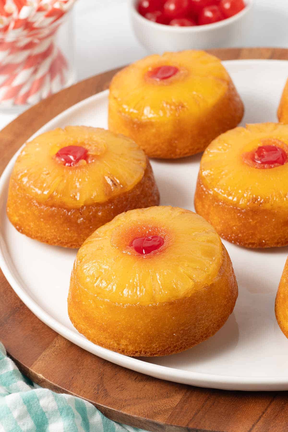 Mini pineapple upside down cakes on a white plate.