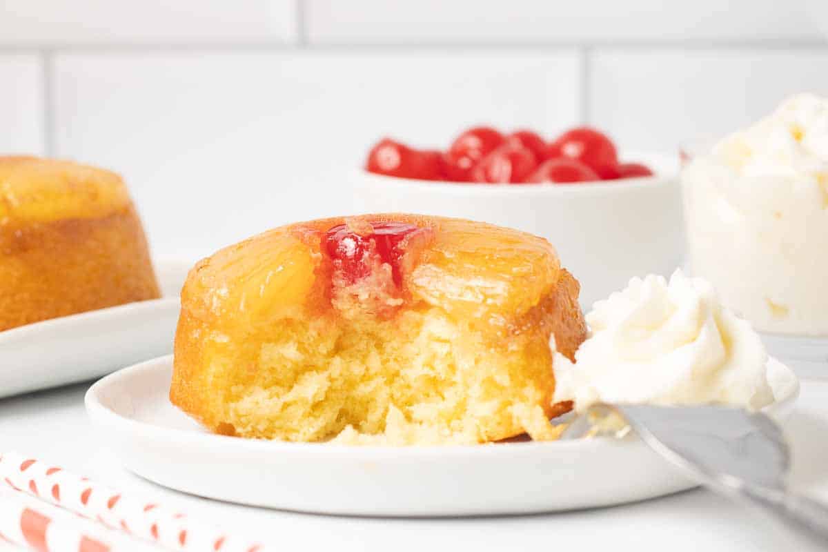 A small pineapple upside down cake on a plate with a bite missing.