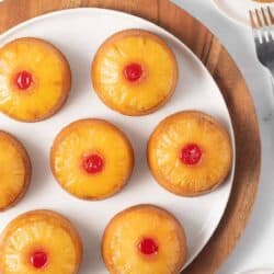 Mini pineapple upside down cakes on a white plate.