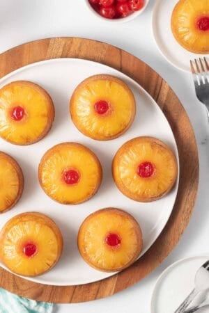 Mini pineapple upside down cakes on a white plate.