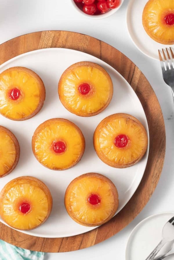 Mini pineapple upside down cakes on a white plate.