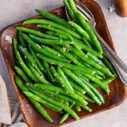 Sauteed green beans on a wood platter.