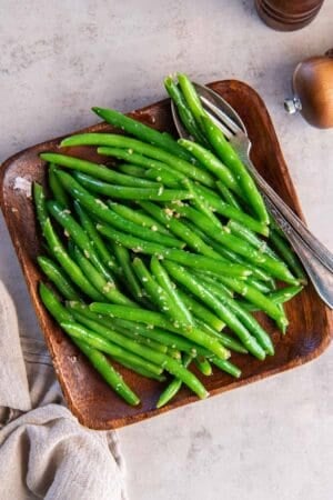 Sauteed green beans on a wood platter.