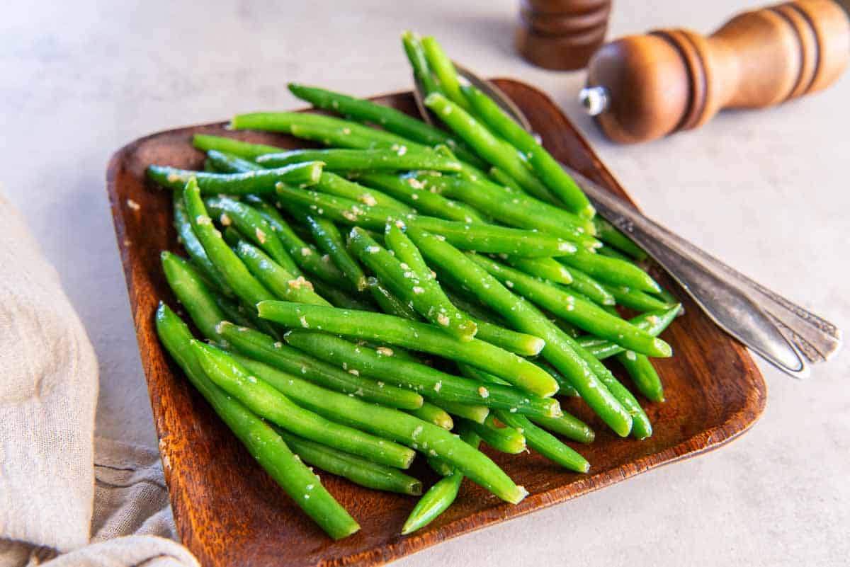 Sauteed green beans on a wood platter.