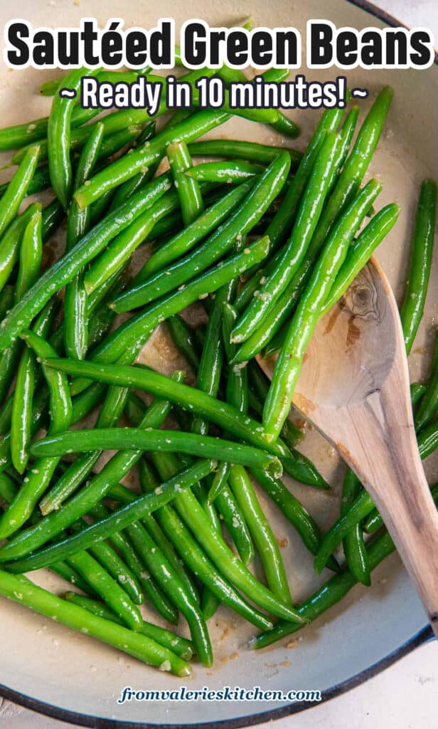 A wooden spoon resting in a pan of sauteed green beans with text.