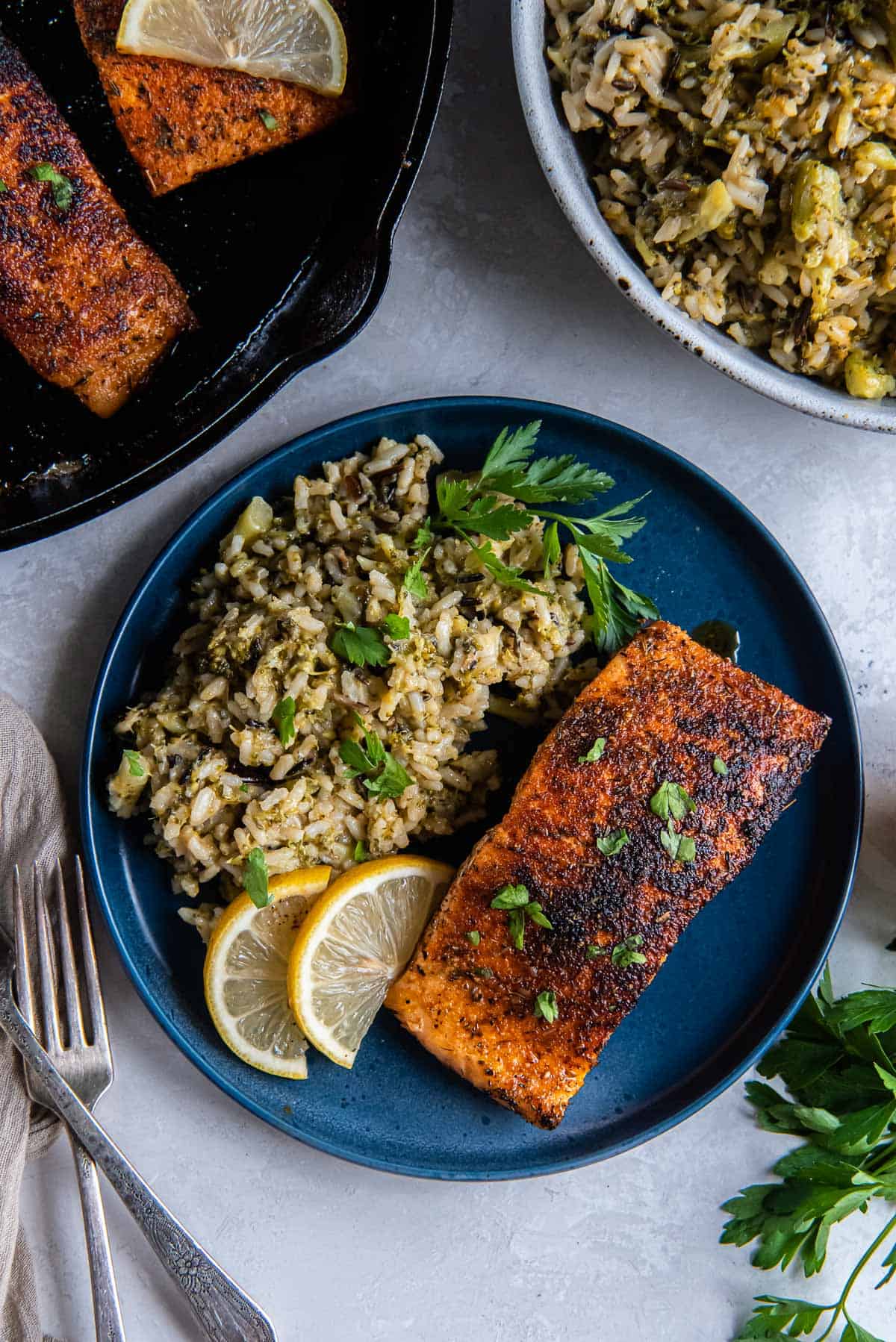 Blackened salmon on a plate with rice next to a cast iron skillet.