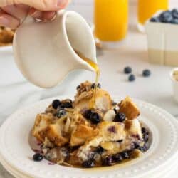 Maple syrup pouring on to a serving of blueberry French toast casserole.