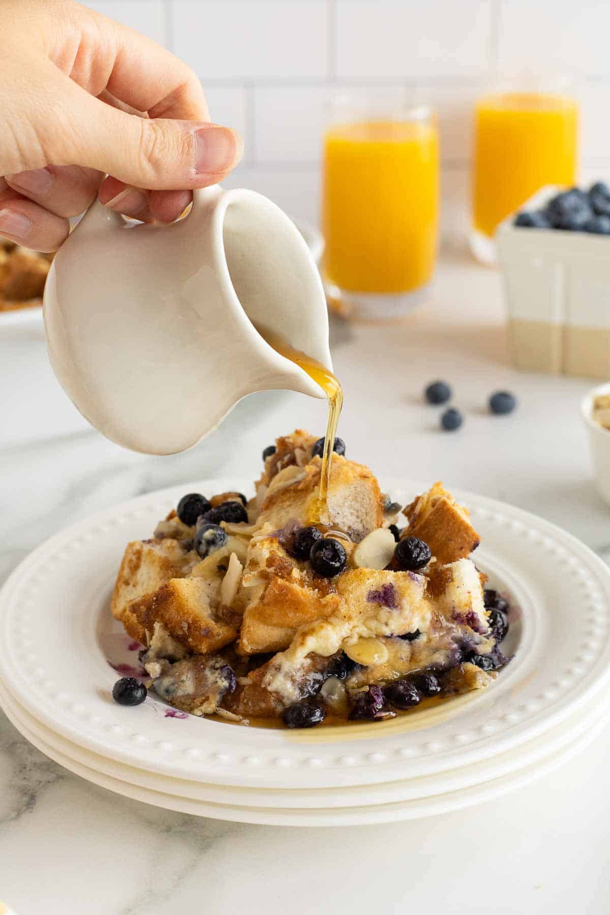 Maple syrup pouring on to a serving of blueberry French toast casserole.