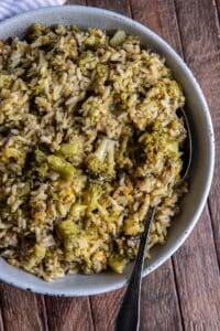 A serving spoon resting in a bowl of broccoli cheese rice.