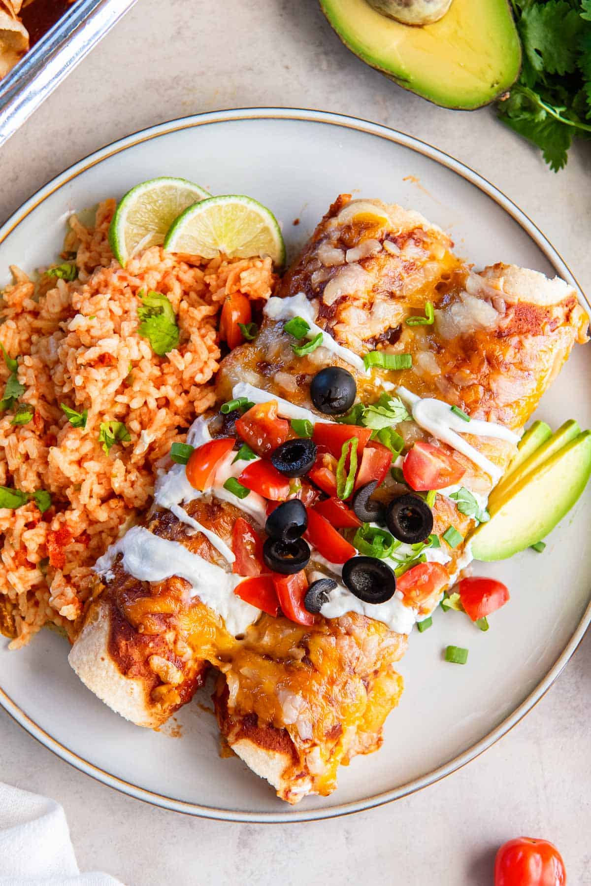 Two chicken enchiladas on a dinner plate with mexican rice.