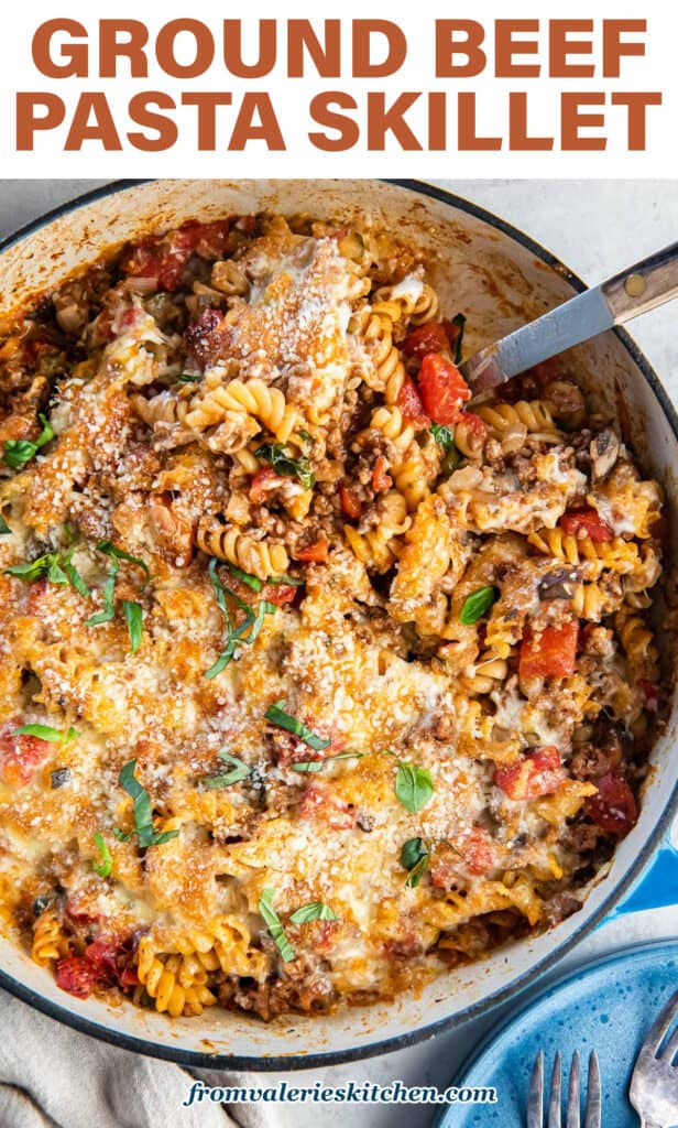 A spoon resting in a skillet of ground beef pasta with text.