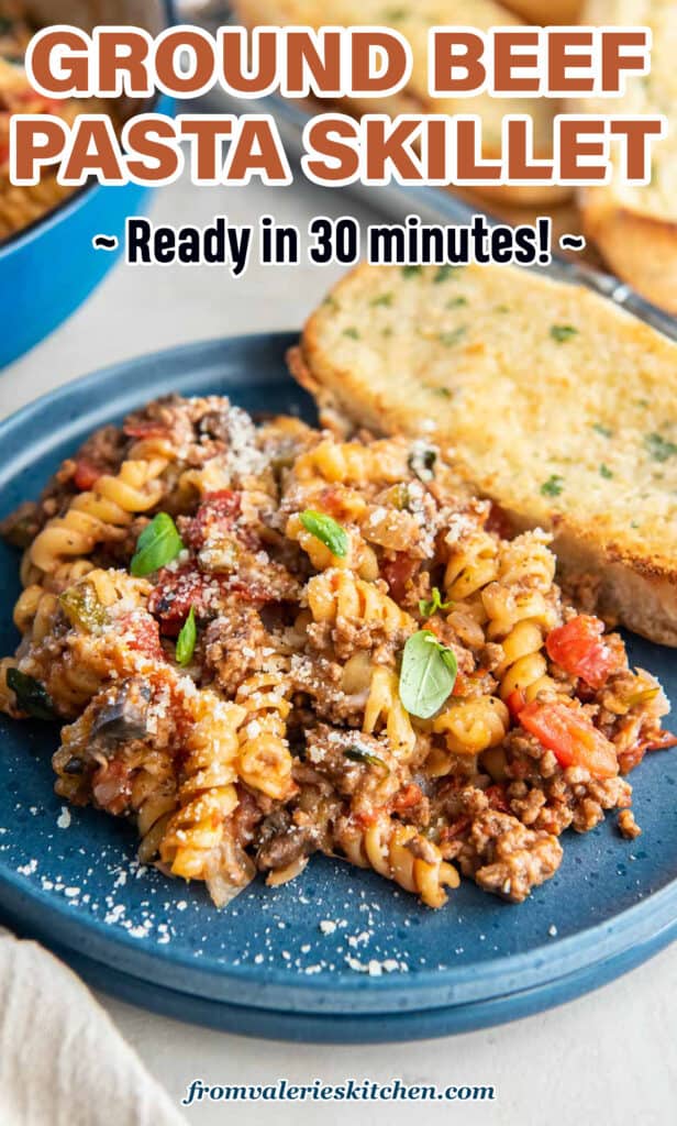 A serving of ground beef pasta on a blue plate with garlic bread with text.