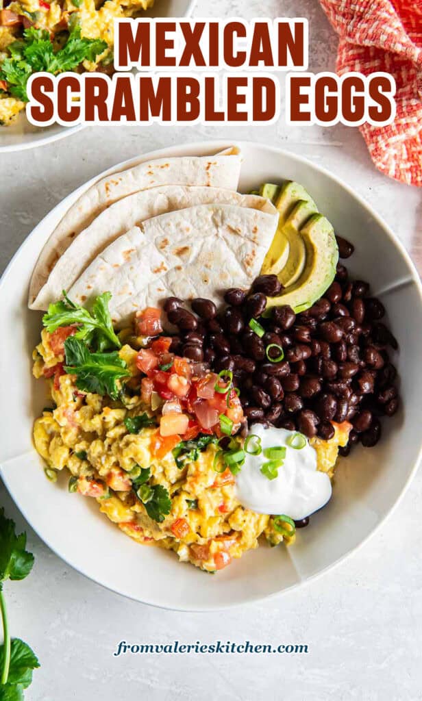 Mexican scrambled eggs in a white bowl with black beans, salsa, and a folded flour tortilla with text.