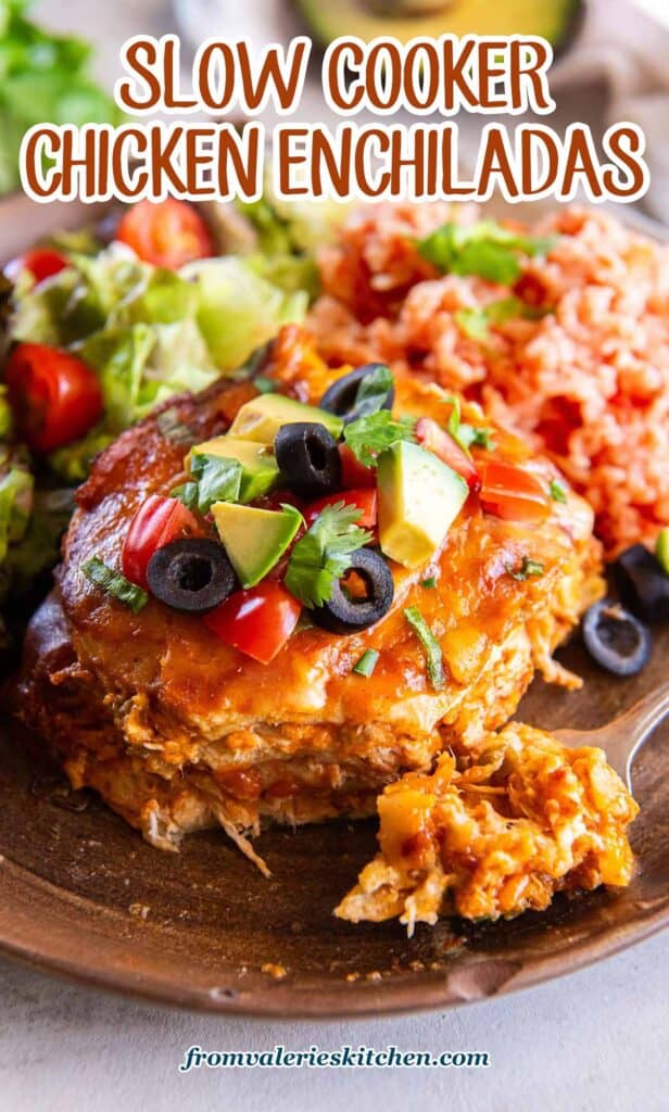 A fork resting on a plate with a serving of slow cooker chicken enchiladas, rice, and salad with text.