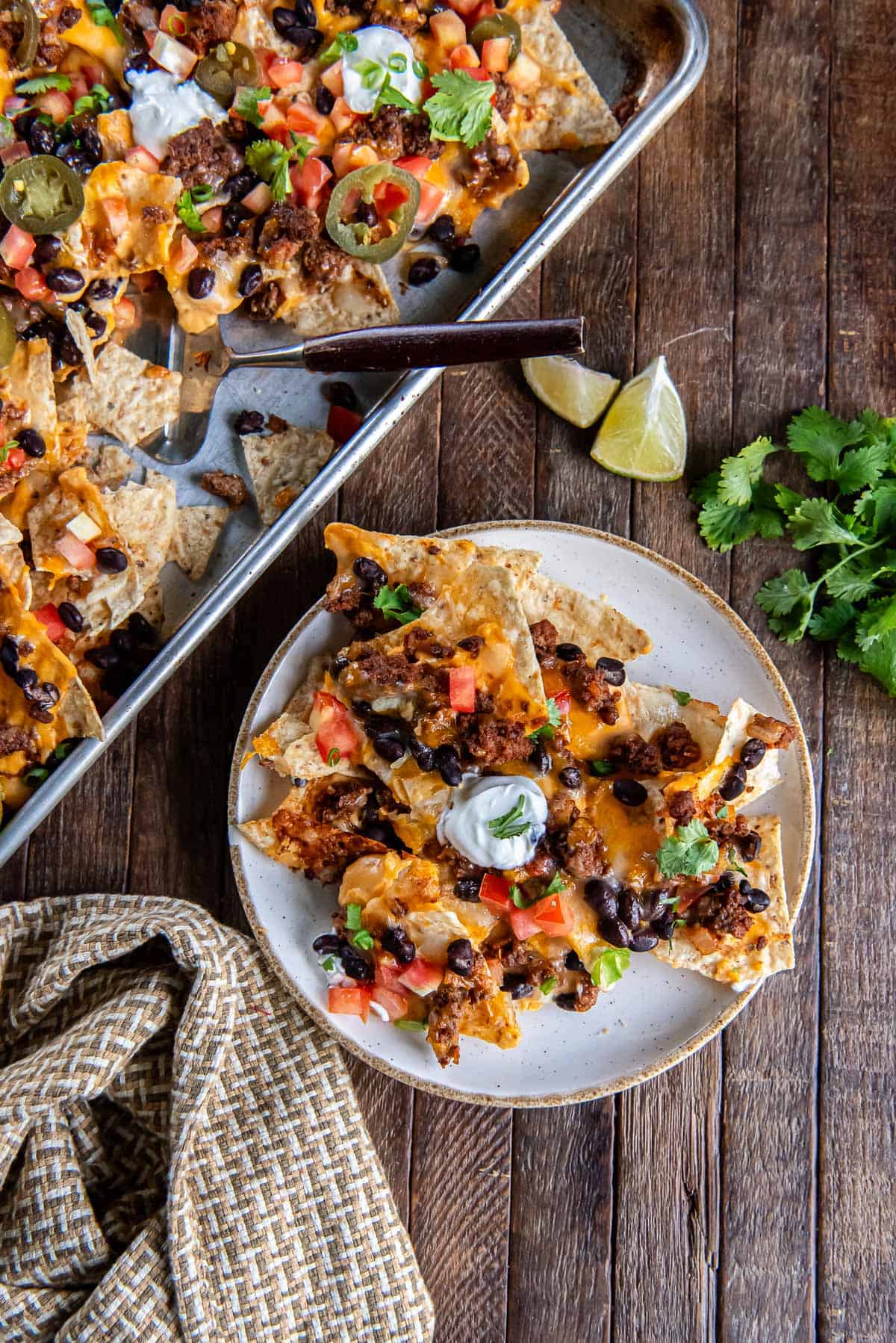 A serving of super nachos on a plate next to a sheet pan.