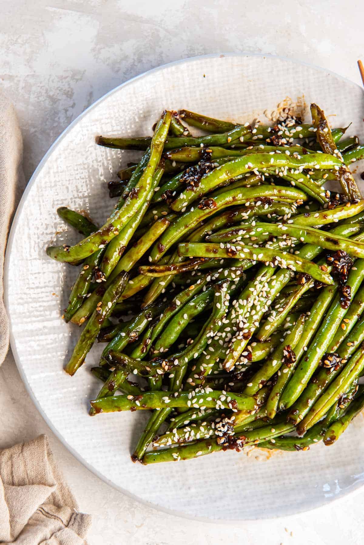 Asian green beans topped with sesame seeds in a white bowl.