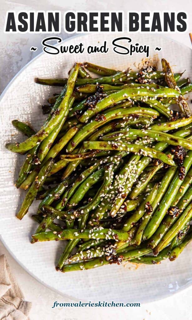 Asian green beans topped with sesame seeds in a white bowl with text.