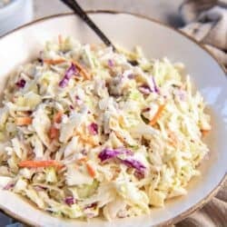 A spoon resting in a bowl of coleslaw.