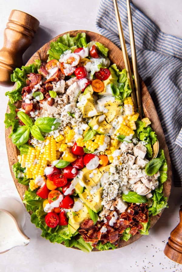 Summer cobb salad topped with basil buttermilk ranch in a wood bowl.