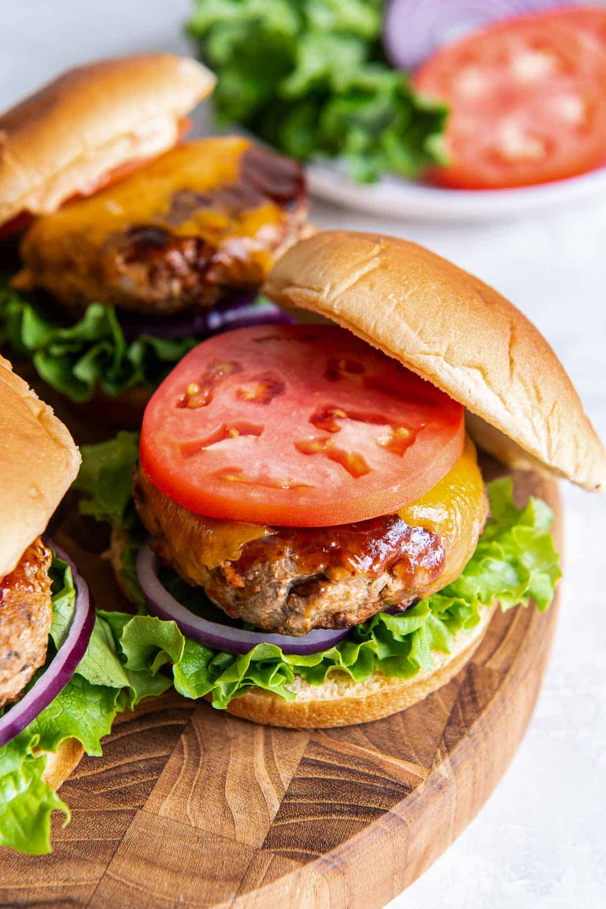 A turkey burger on a wood platter with the top bun resting halfway off the top.
