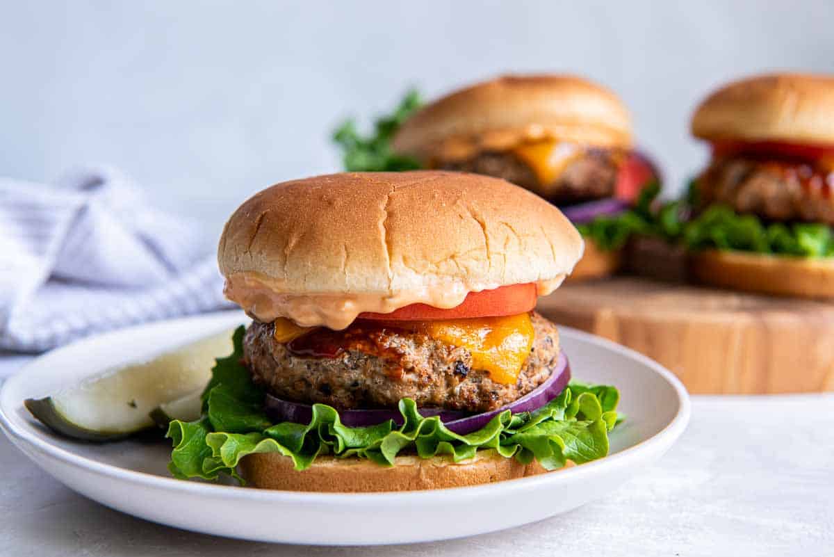 A turkeyburger with lettuce and tomato on a white plate.