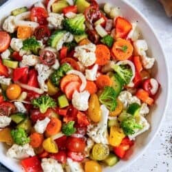 Marinated vegetables in a white bowl next to a blue kitchen cloth.