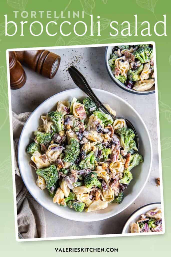 A spoon resting in a serving bowl filled with tortellini broccoli salad with text.