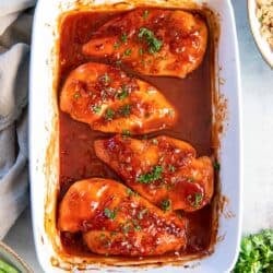 Chicken breasts topped with catalina dressing in a baking dish.